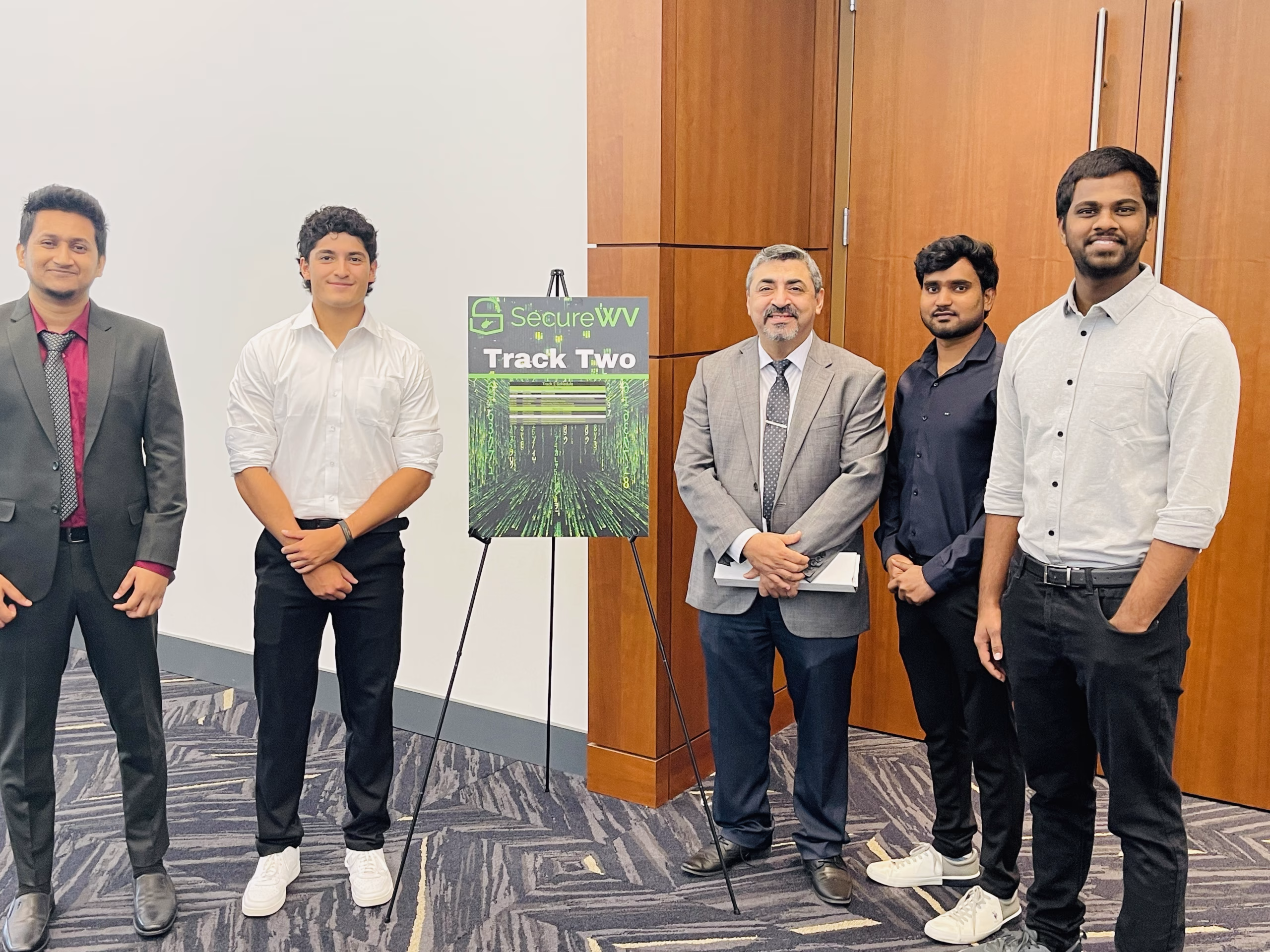 Students standing with Dr. Al-Sinayyid an an easel with a poster at the Secure WV conference