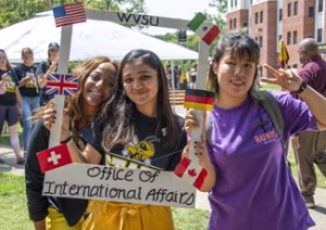 Photo of students outside at an event holding a sign that says Office of International Affairs