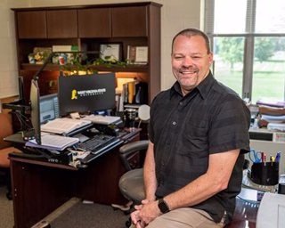 Michael Casey picture of Michael Casey seated on desk in his office, program coordinator