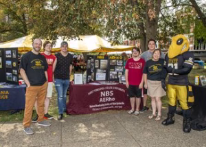 Photo of students at an event standing next to a table with a maroon tablecloth