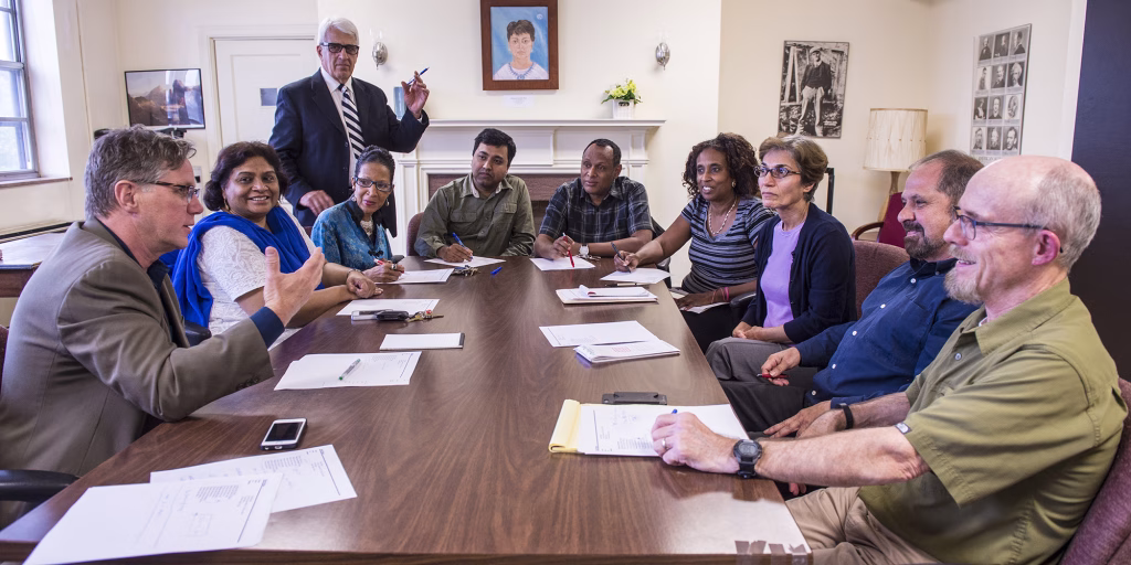 Photo of the WVSU Educational Policies Committee in a meeting. Faculty memers are sitting around a conference room table talking.
